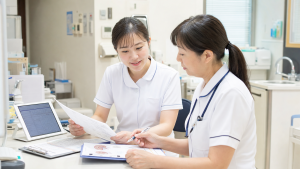脳神経内科クリニックで問診資料と検査説明を確認する看護師